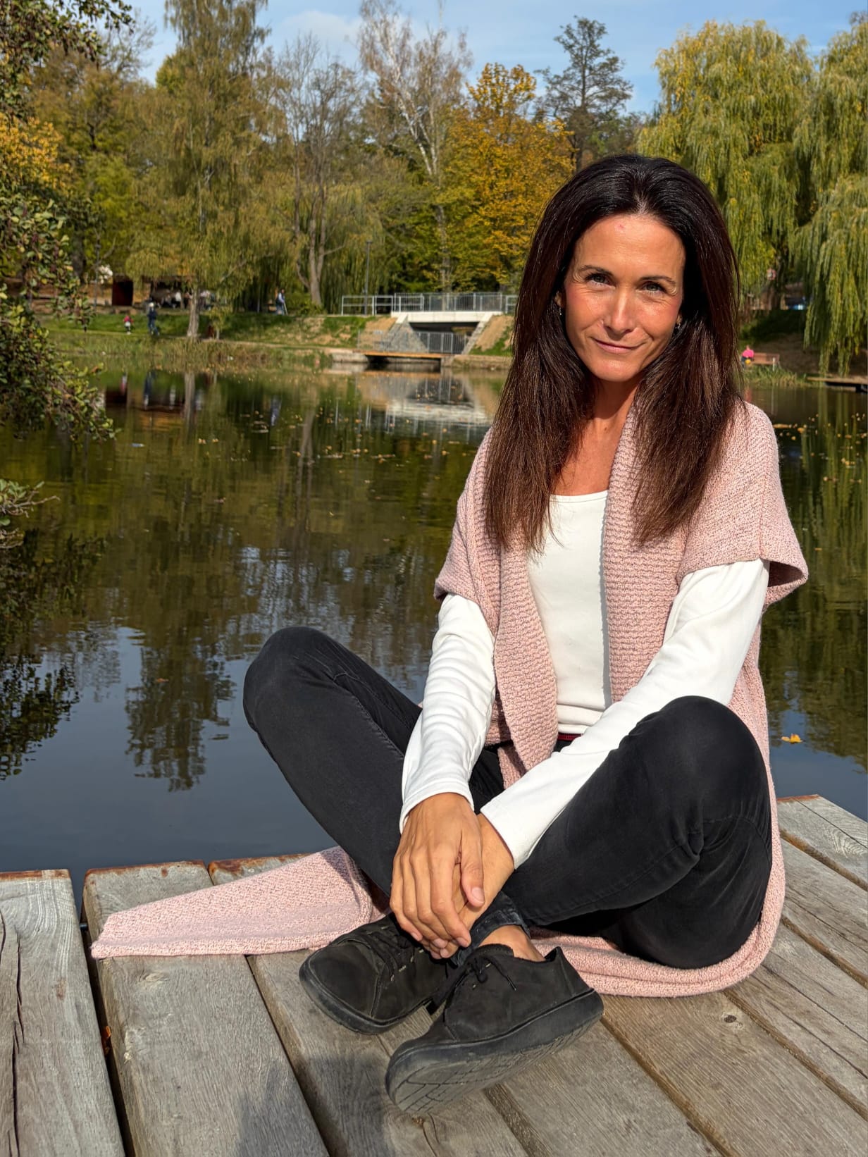 Jana Lahodová sedí na molu u vody v podzimní přírodě